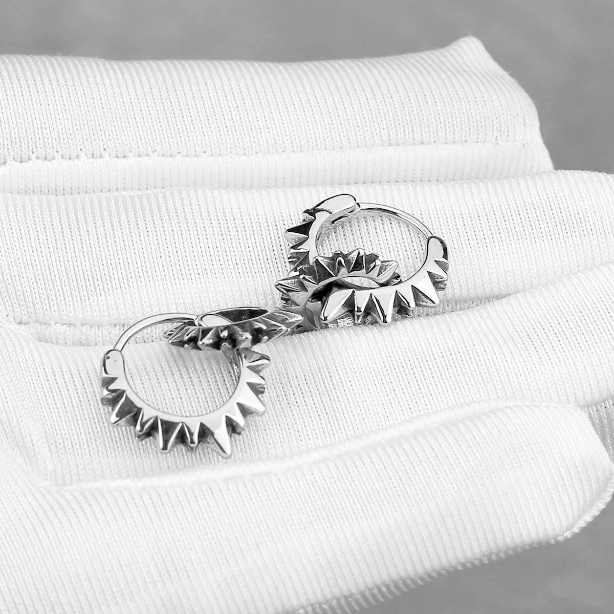 Polished steel round hoop earrings with a 2.5cm diameter on a plain background.