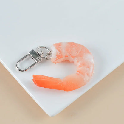 White PVC shrimp-shaped keychain with door buckle on a blue background.