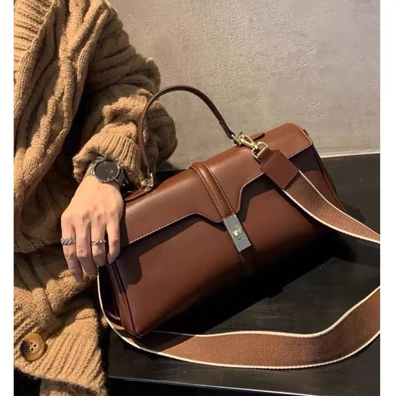 Women's cylindrical cowhide messenger bag in black with multiple internal compartments and shoulder strap
