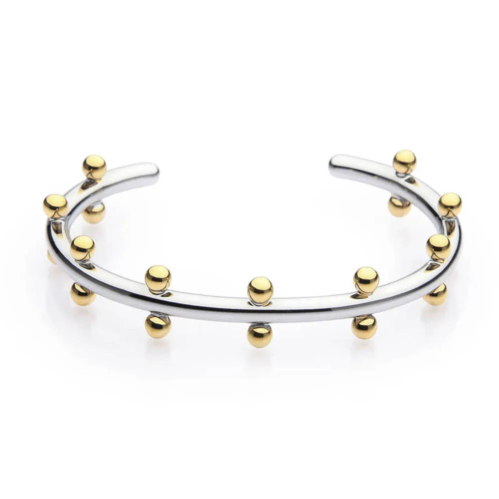 Close-up of a textured stainless steel C-shaped bracelet with rivet-shaped bean beads in a gold finish.