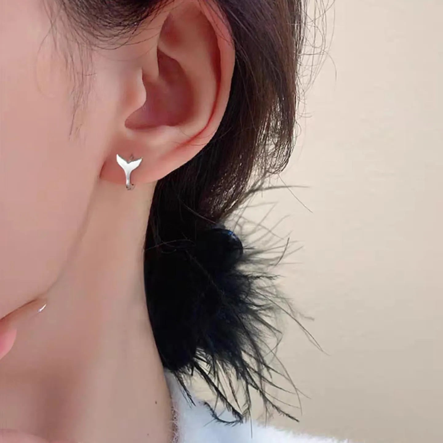 A pair of simple fishtail design earrings with an electroplated metallic finish, shown in white gold and yellow gold colour options.