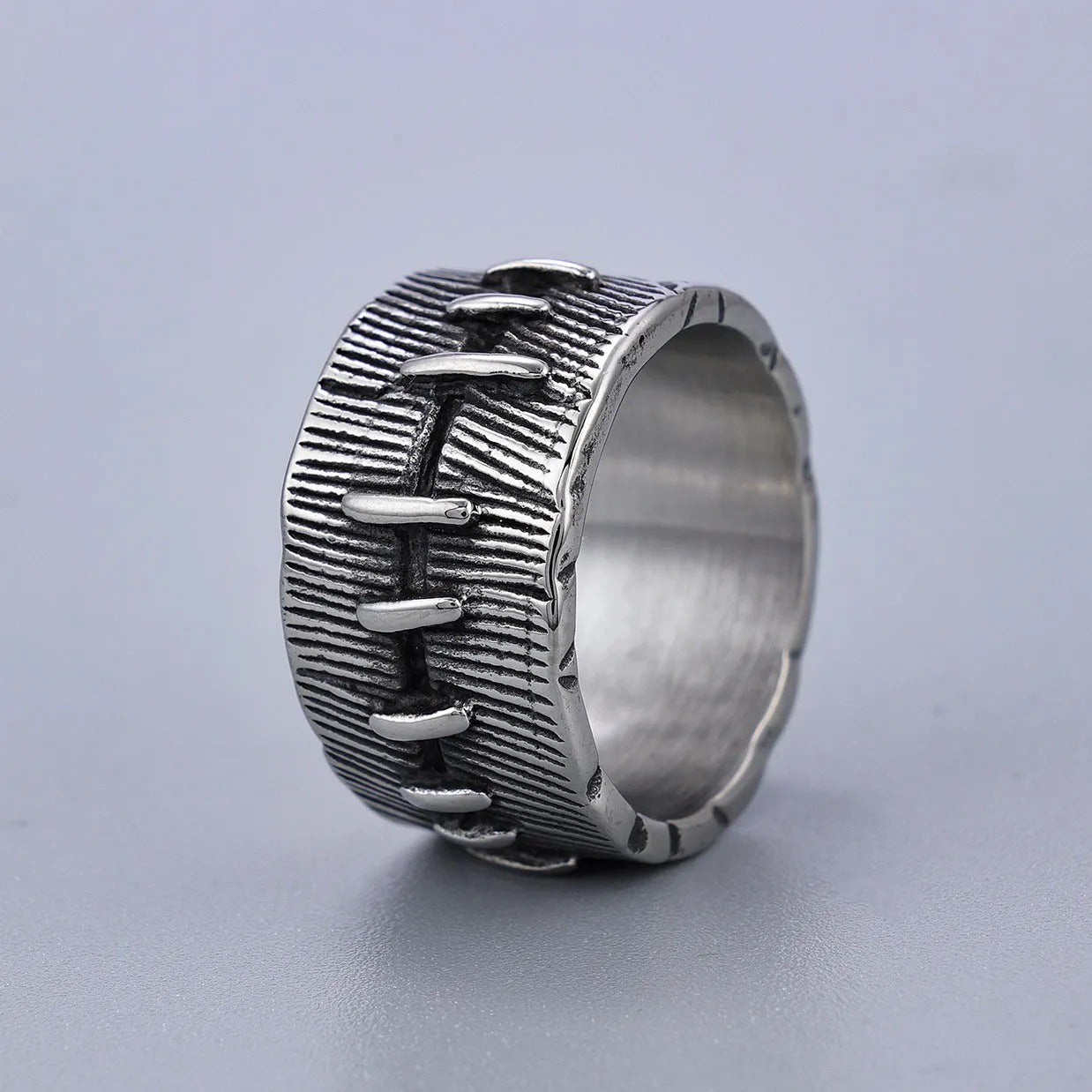 Dark geometric titanium steel punk ring showing U-shape and double ring design with stitched texture.
