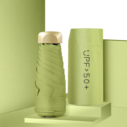 Compact flat-folded sun umbrella in a solid colour, shown next to a hand for scale.