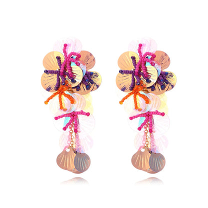 Handmade string bead flower earrings with exaggerated floral shapes in rose and purple colours, showing mixed materials and nickel-free hooks
