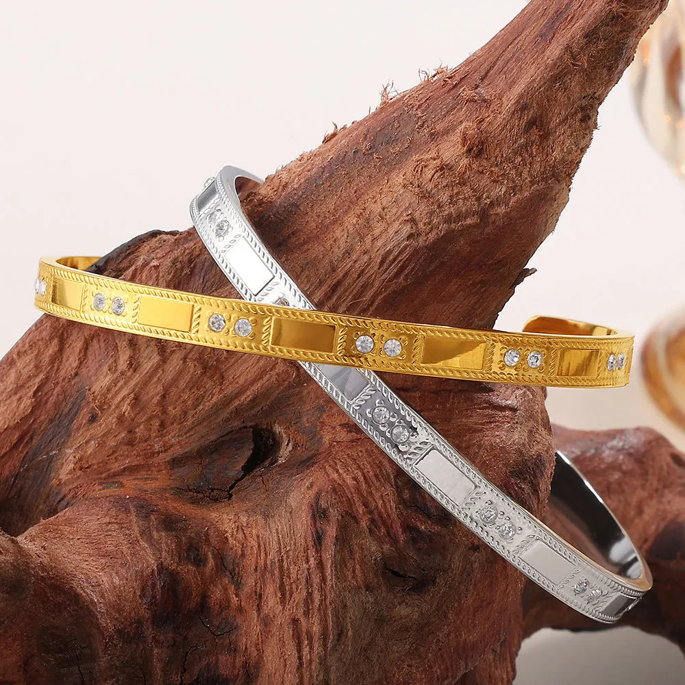 Stainless steel open-end bracelet with a buckle clasp in a choice of gold, silver, or zirconium gold electroplated finishes.