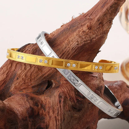 Stainless steel open-end bracelet with a buckle clasp in a choice of gold, silver, or zirconium gold electroplated finishes.