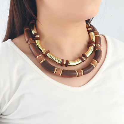 Layered bohemian jewellery set with a large round wooden pendant necklace and matching bracelet on a table.