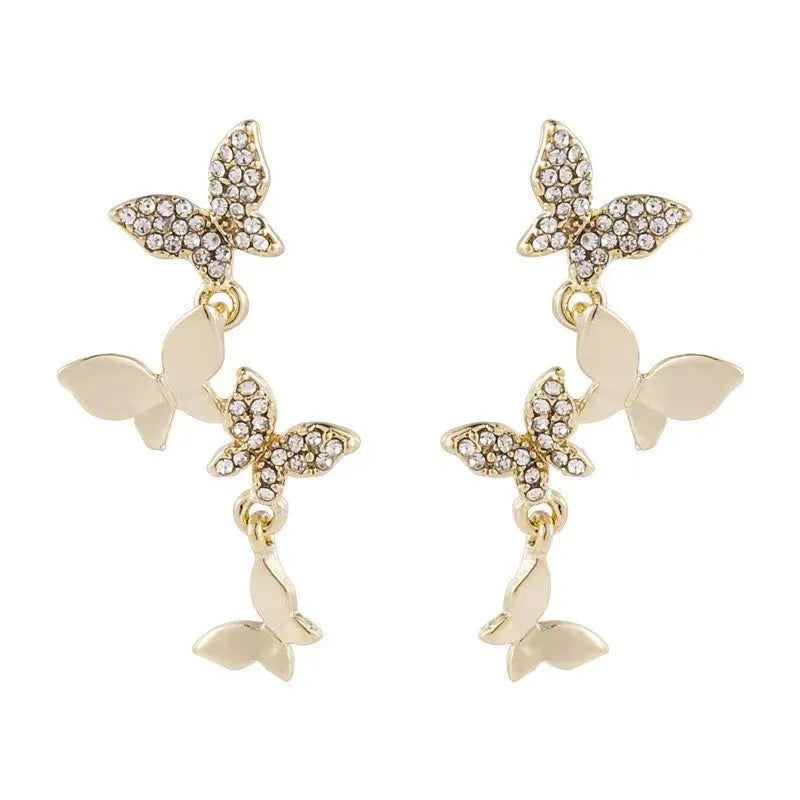 Women's gold copper butterfly drop earrings showing four-element dangle design