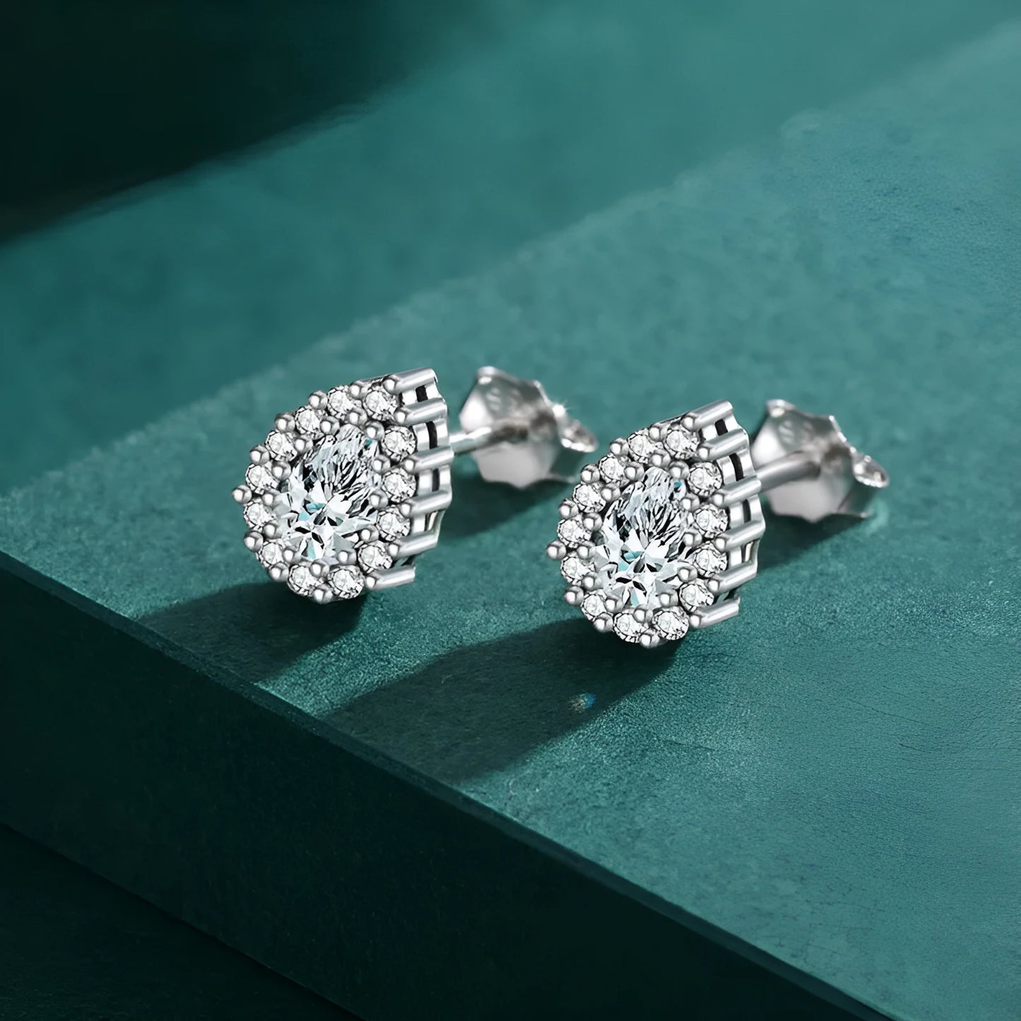 A pair of drop-shaped sterling silver ear studs with a diamond-cut finish.