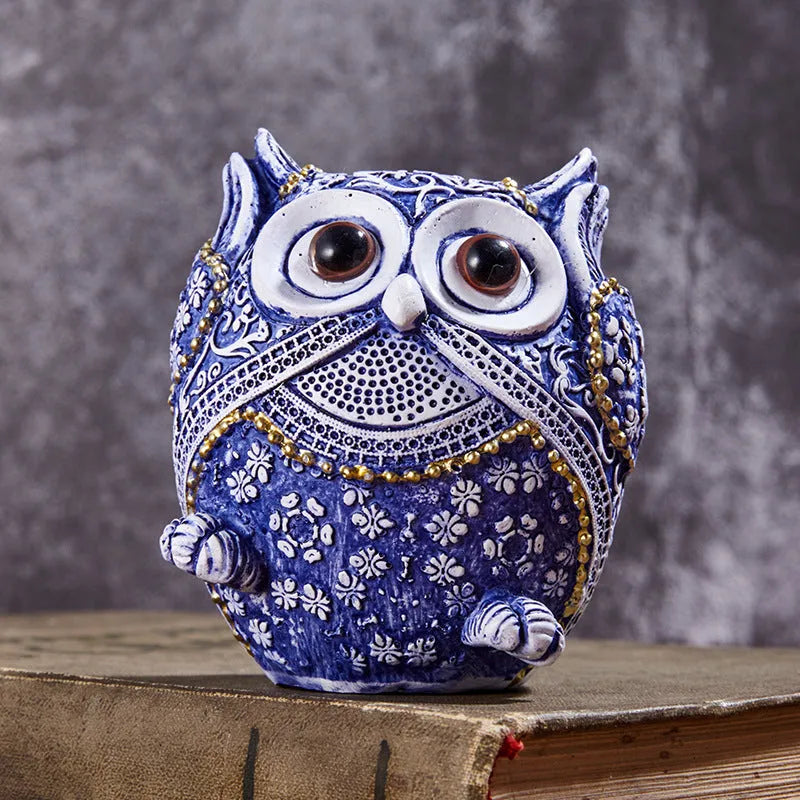 Three blue and white owl resin ornaments with hand-painted pastoral design on wooden surface