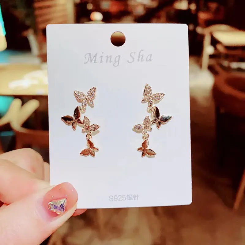 Women's gold copper butterfly drop earrings showing four-element dangle design
