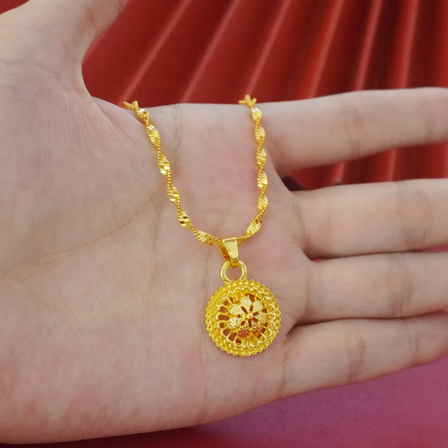 Gold-plated three-piece jewellery set showing necklace with floral pendant, matching earrings, and ring on a grey background.