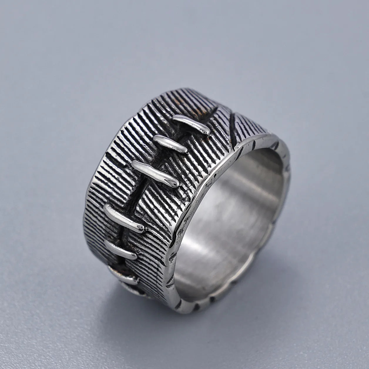 Dark geometric titanium steel punk ring showing U-shape and double ring design with stitched texture.