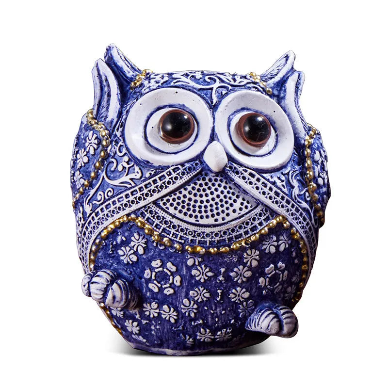 Three blue and white owl resin ornaments with hand-painted pastoral design on wooden surface