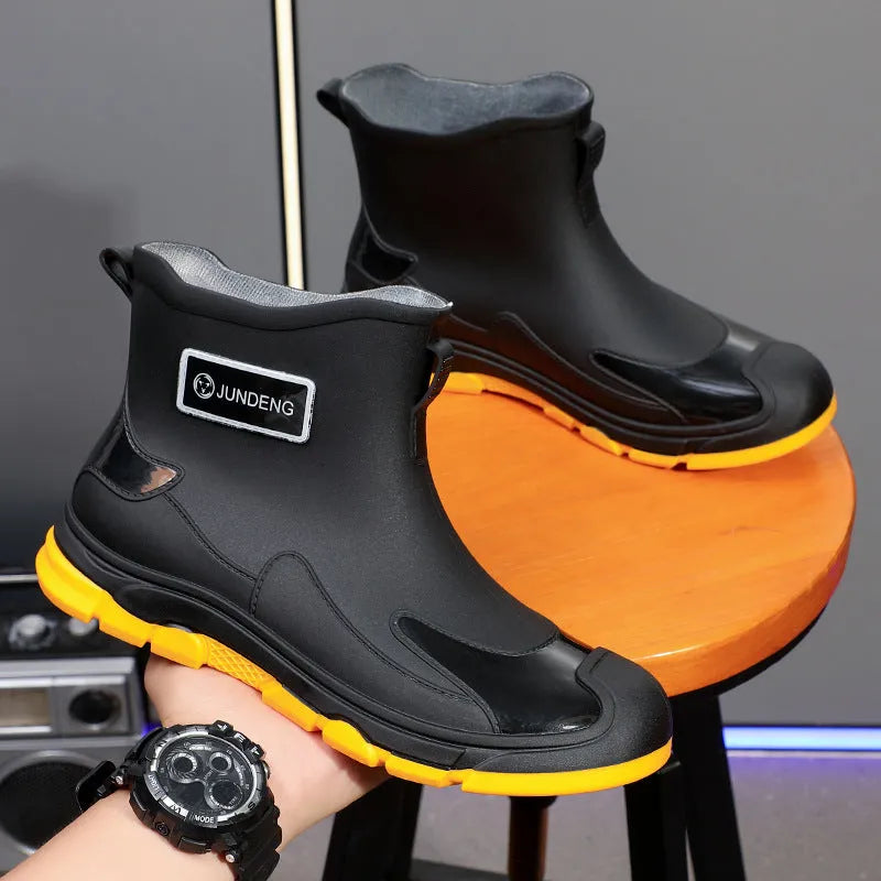 Minimalist black PVC waterproof wading boots with flat heel and round toe on a neutral background.
