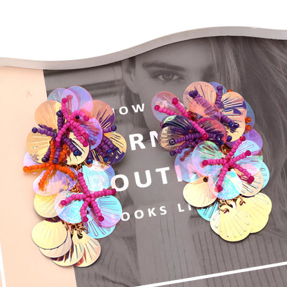 Handmade string bead flower earrings with exaggerated floral shapes in rose and purple colours, showing mixed materials and nickel-free hooks