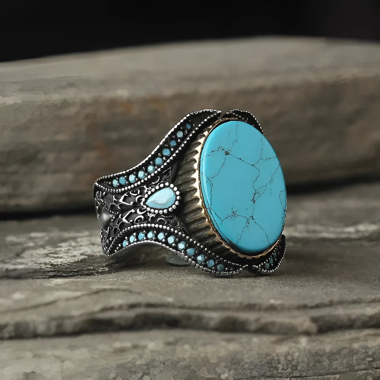 A round men's alloy ring in antique silver finish with turquoise colour accents on a plain background.