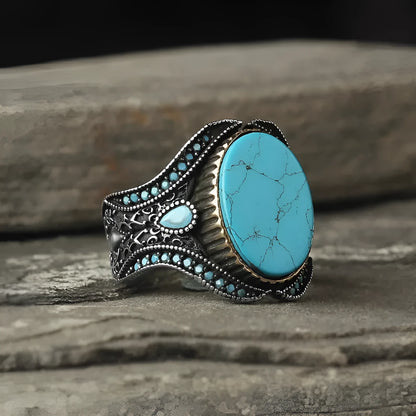 A round men's alloy ring in antique silver finish with turquoise colour accents on a plain background.