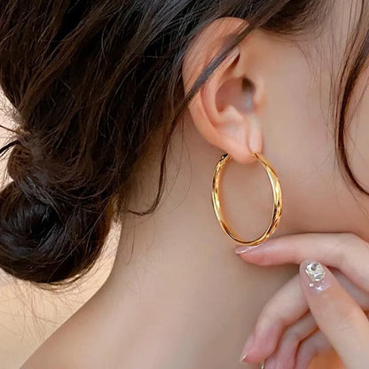 A pair of large, circular metal earrings in gold or silver colour, measuring 40mm.