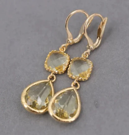 Gold geometric long fringe earrings with crystal water droplets on a white background.