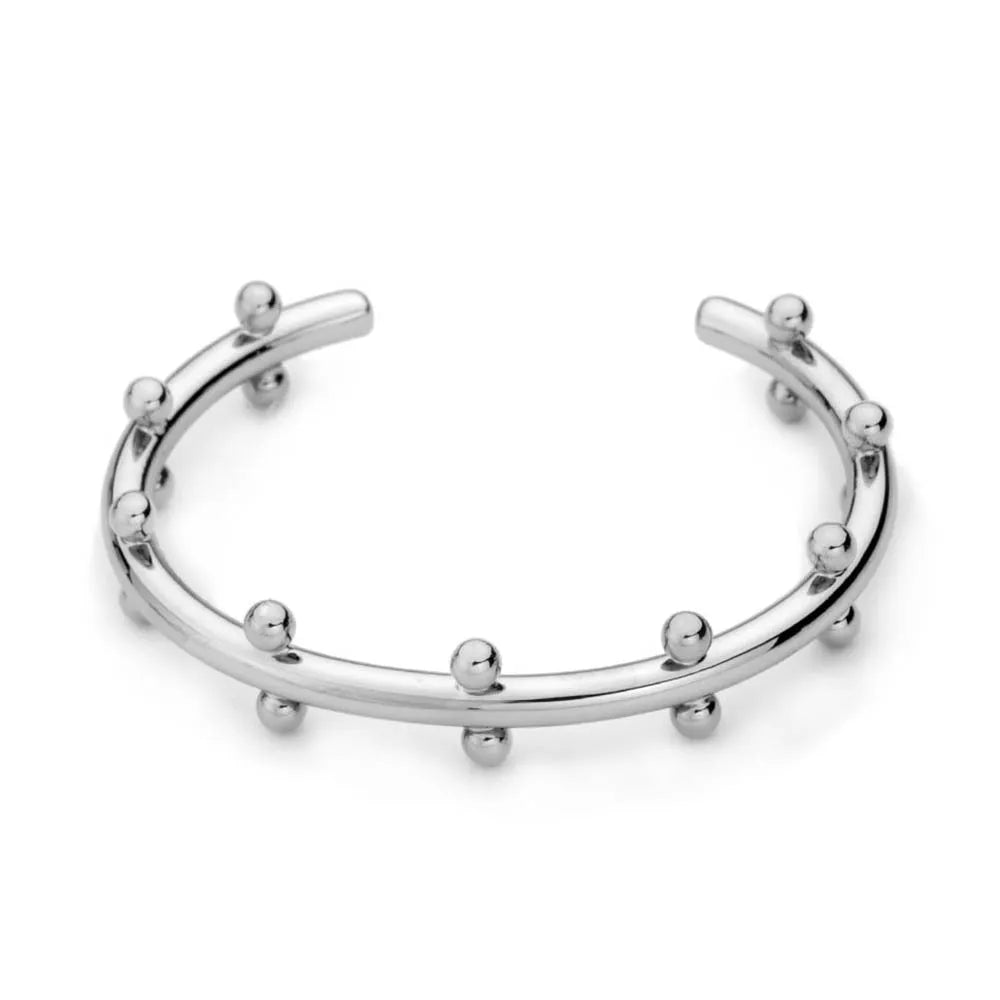 Close-up of a textured stainless steel C-shaped bracelet with rivet-shaped bean beads in a gold finish.