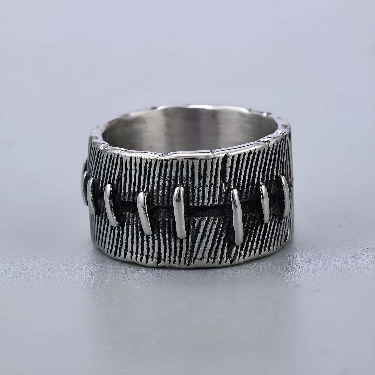 Dark geometric titanium steel punk ring showing U-shape and double ring design with stitched texture.