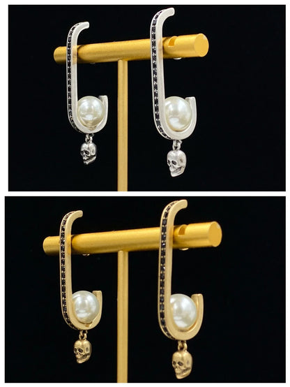 Pair of gold-tone earrings with a skull-shaped design, featuring pearls and diamonds