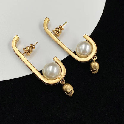 Pair of gold-tone earrings with a skull-shaped design, featuring pearls and diamonds