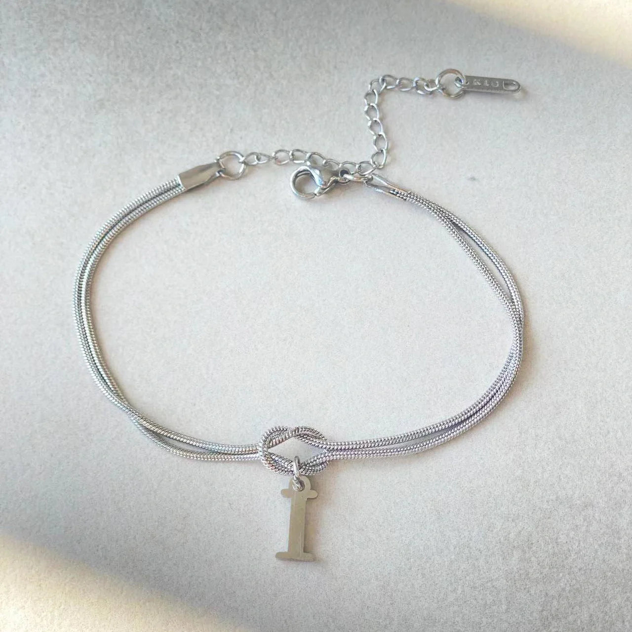 Elegant letter charm bracelets for women in gold and silver tones, featuring a delicate snake chain design and personalised letter charms.