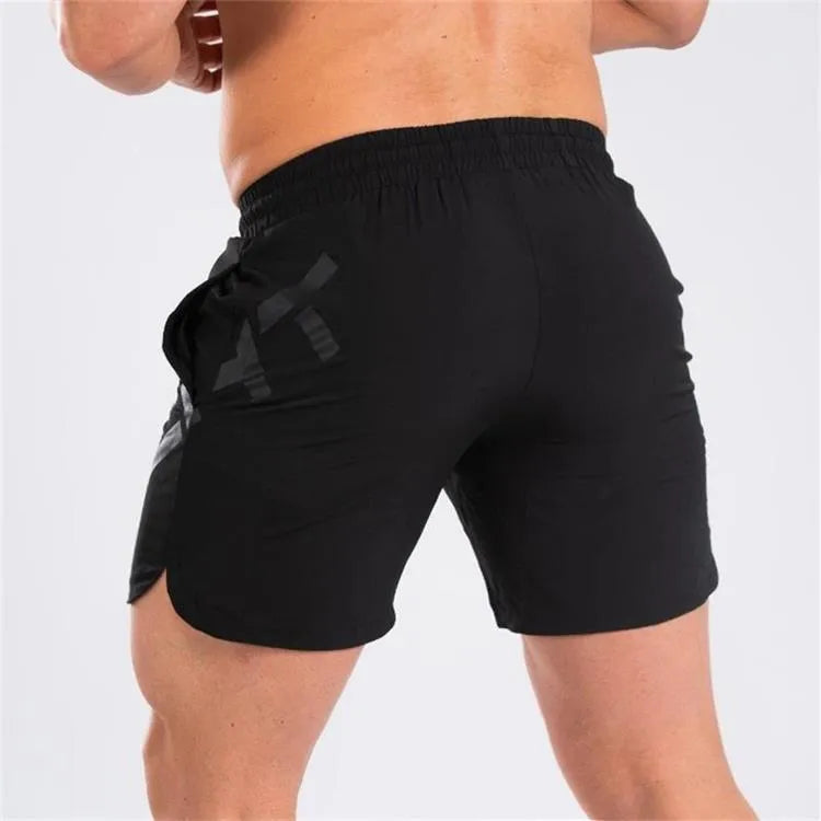 Man wearing black knee-length nylon training shorts with an elastic mid waist.