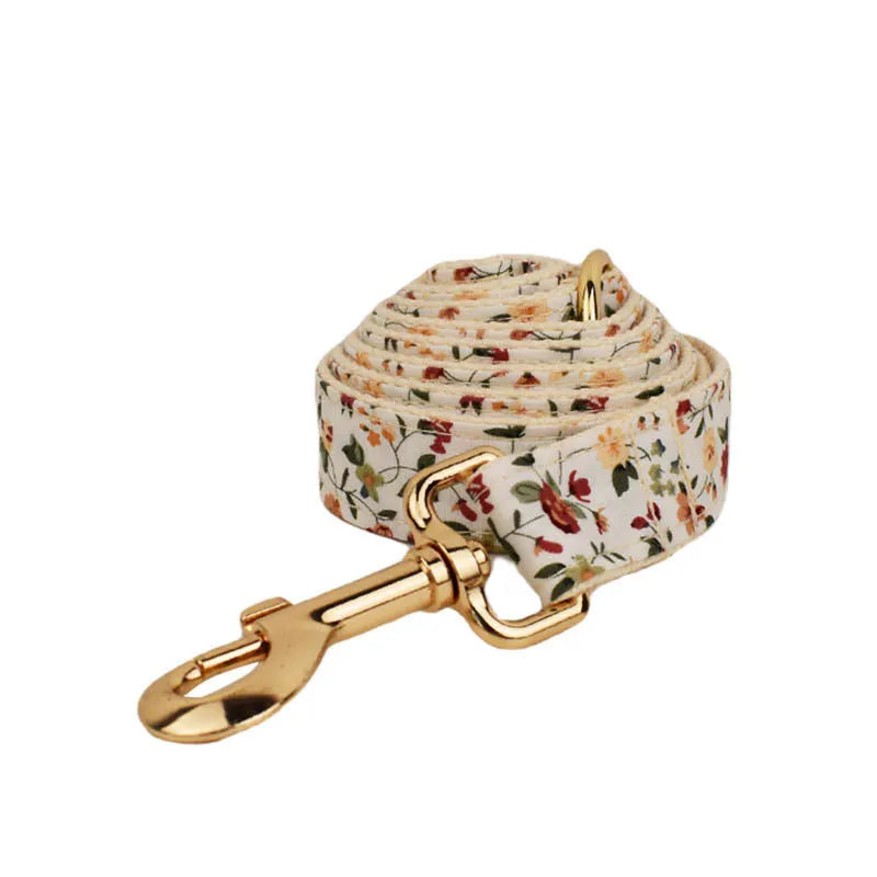 Small white flower decoration on a cloth dog collar and leash set with matching vest and bow.