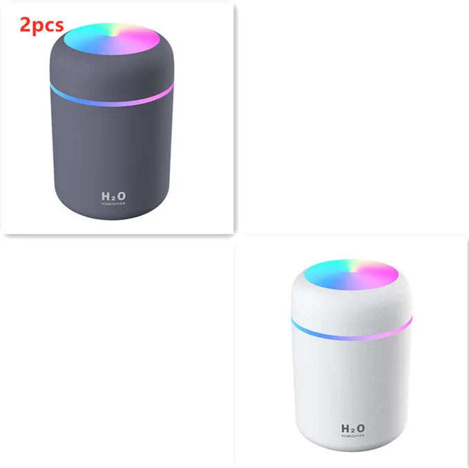 Pink USB desktop humidifier with LED lights and water tank on wooden desk
