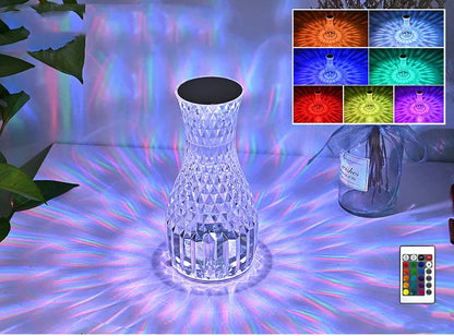 Vase-shaped crystal table lamp with remote control on a bedside table, showing diamond-like glow and USB charging port.