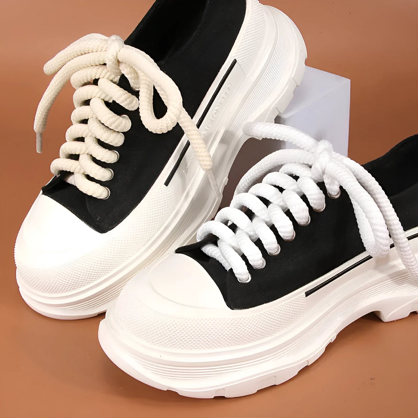 Round woven white, beige, and black shoelaces for bread shoes showing different lengths on a flat surface.