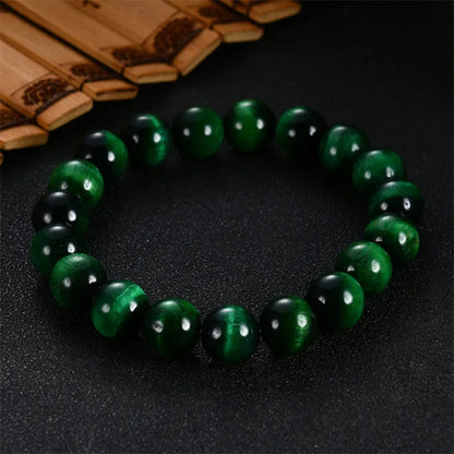 Green tiger's eye stone bracelet with geometric beads on a wrist.