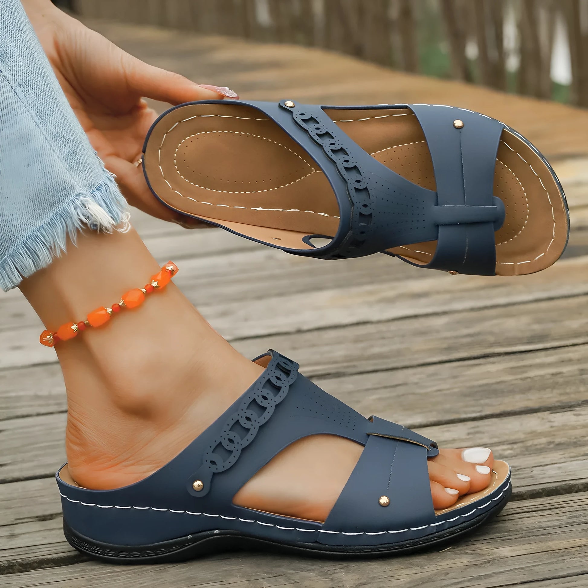 Beige Roman style slippers with a fish mouth toe, slope heel, and rubber sole.