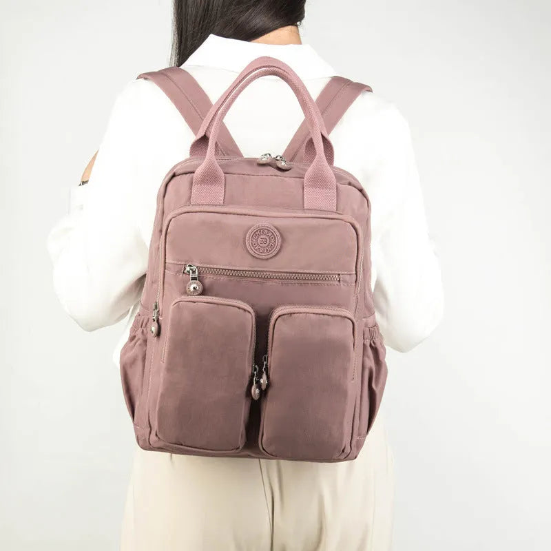 Women's waterproof travel backpack with large capacity multifunctional organisation featuring laptop sleeve, camera compartment, and internal zippered pockets in black, grey, or lotus root purple