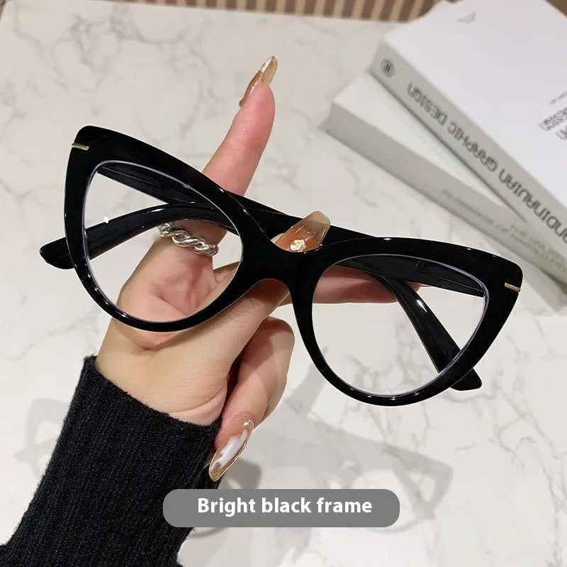 Women's black floral cat's eye reading glasses with large frames on a wooden table.