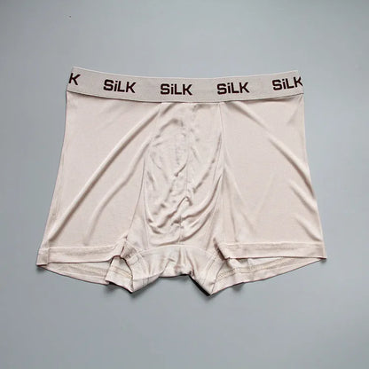 Man wearing loose-fit mid-waist shorts in navy blue silk fabric.