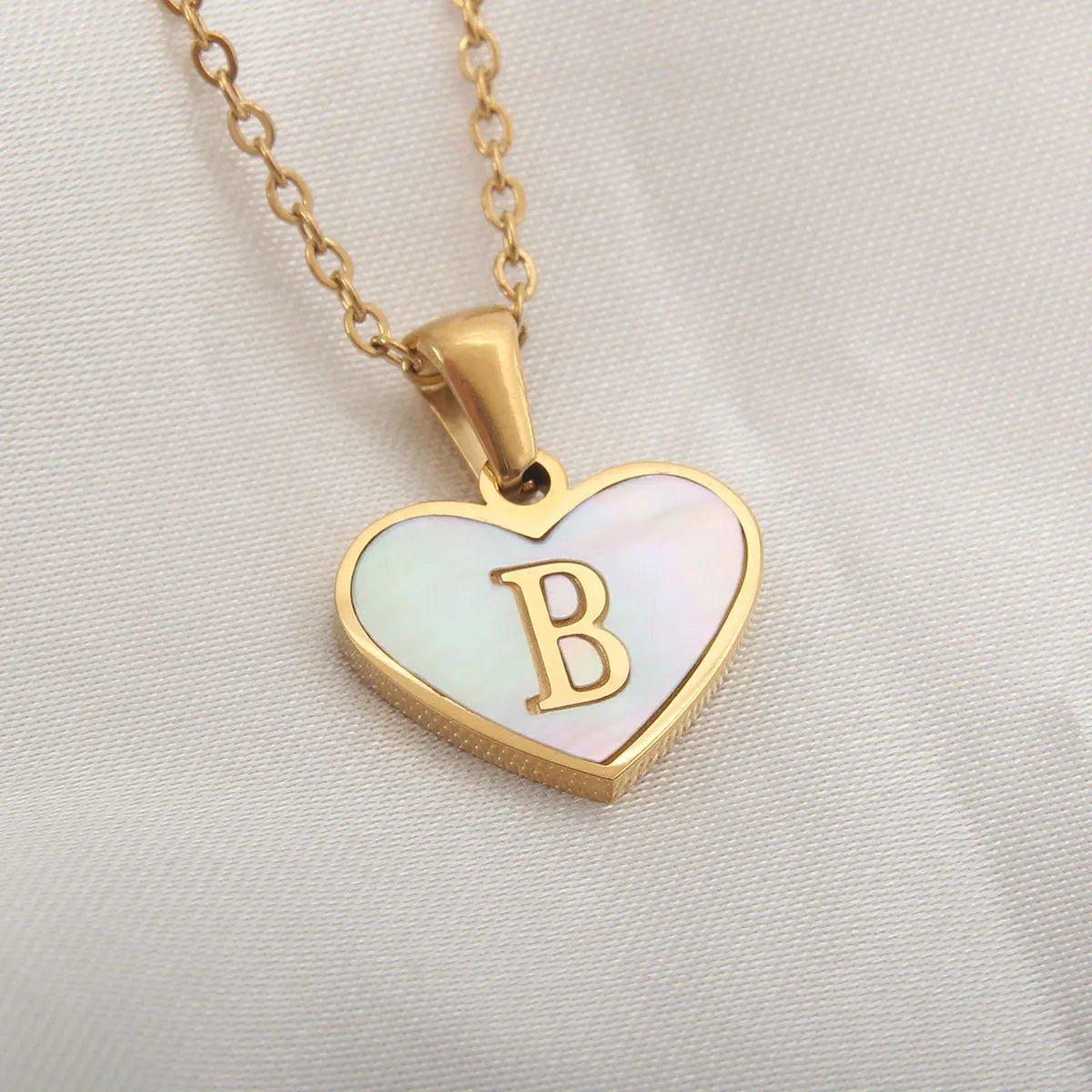 Gold-plated heart necklace with white shell pendant showing letter personalisation option