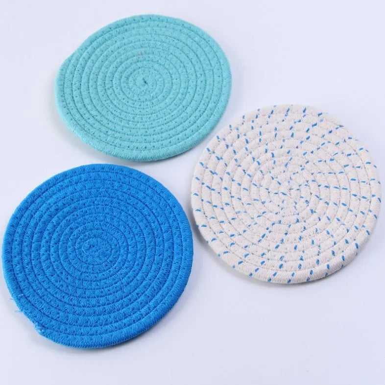 Three round grey cotton cord coaster placemats on a wooden table, each 18cm in diameter.