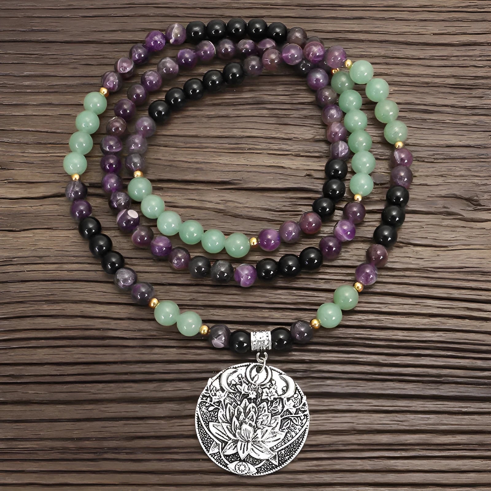 Long stone bead necklace with alloy lotus pendant and matching bracelet set on a background.