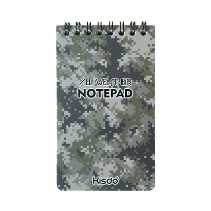 Spiral-bound waterproof notepad in camouflage colour, open on a wooden surface with a pen.