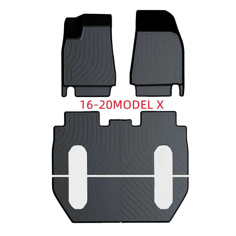 Custom black rubber floor mats fitted in a Tesla Model 3, showing deep grooves and raised edges.