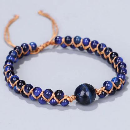 Close-up of a hand-woven geometric bracelet with a blue Tigereye stone on a wrist.