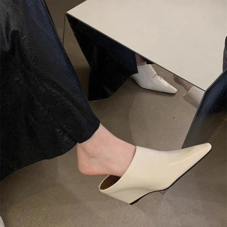 Women's black wind wedge closed toe half slippers showing PU upper and open back.