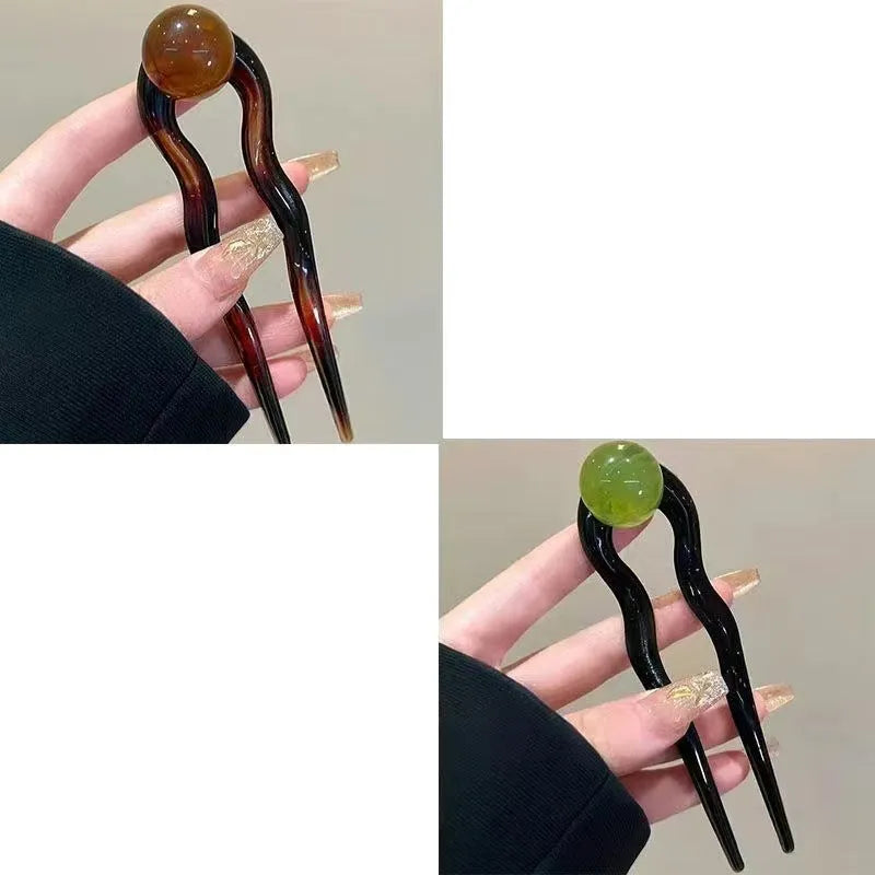 A set of U-shaped acrylic hair barrettes with a simple ball decoration in beige, caramel, and dark grey colours.