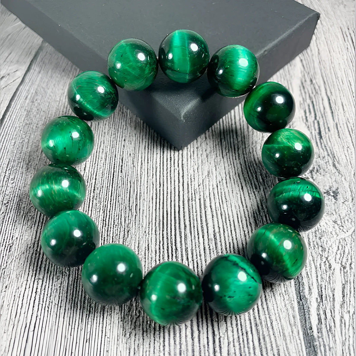 Green tiger's eye stone bracelet with geometric beads on a wrist.
