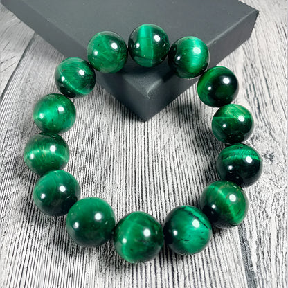 Green tiger's eye stone bracelet with geometric beads on a wrist.