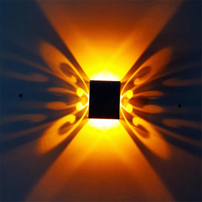 Modern aluminium butterfly-shaped LED wall lamp with colour-changing lights on a plain wall